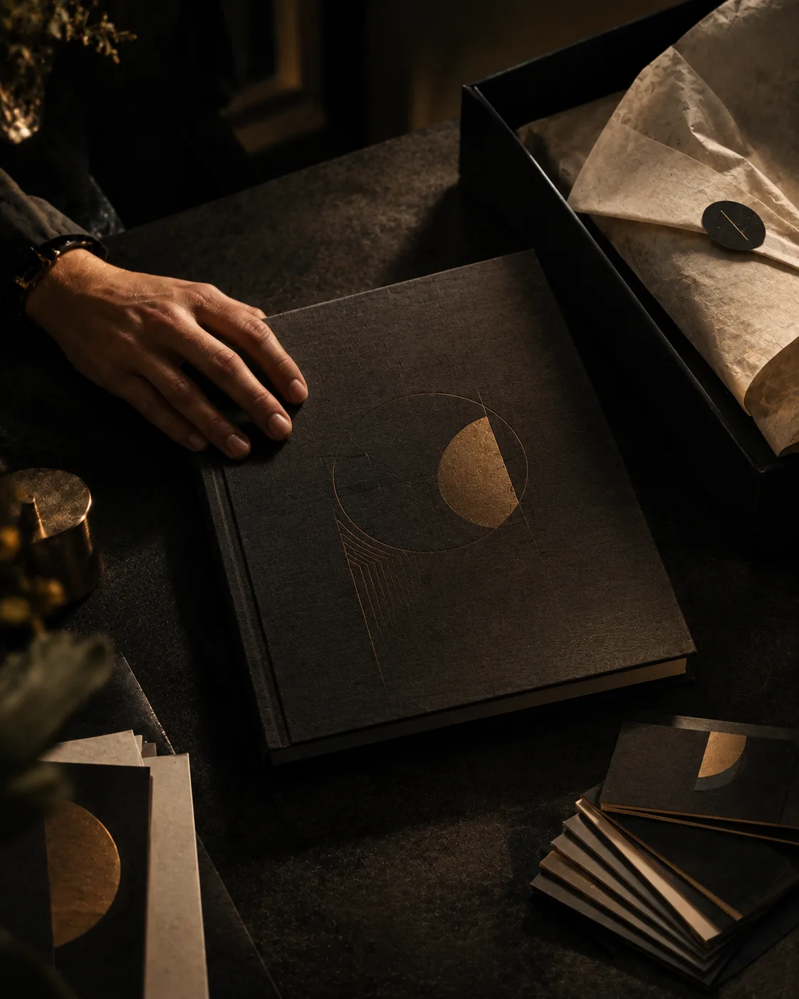 A finished brand book, gold mark blocked on its cover, resting beside the tissue-lined box it ships in.
